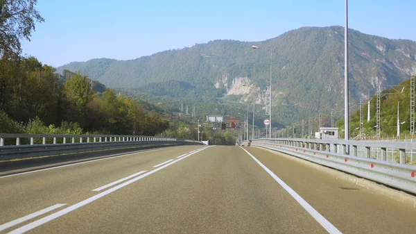 Vista desde un coche en movimiento. carretera entre las montañas en verano. pico de montaña — Foto de Stock