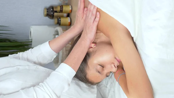 Primer plano. manos de masajista hacen masaje de espalda a hermosa joven — Foto de Stock