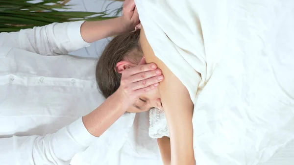 Primer plano. manos de masajista hacen masaje de espalda a hermosa joven — Foto de Stock