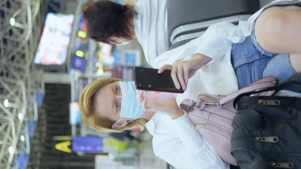 医療用マスクの女性は空港でスマートフォンを使い — ストック写真