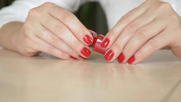 Zamknij kobiece dłonie. kobieta maluje paznokcie czerwonym lakierem do paznokci — Zdjęcie stockowe