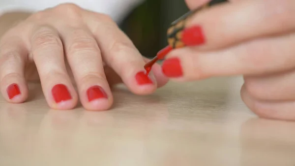 Zamknij kobiece dłonie. kobieta maluje paznokcie czerwonym lakierem do paznokci — Zdjęcie stockowe