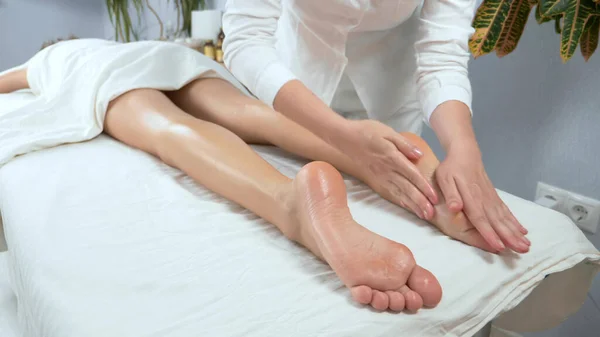 Masöz, uzun bacaklı güzel bir kıza tıbbi ayak masajı yapıyor. — Stok fotoğraf