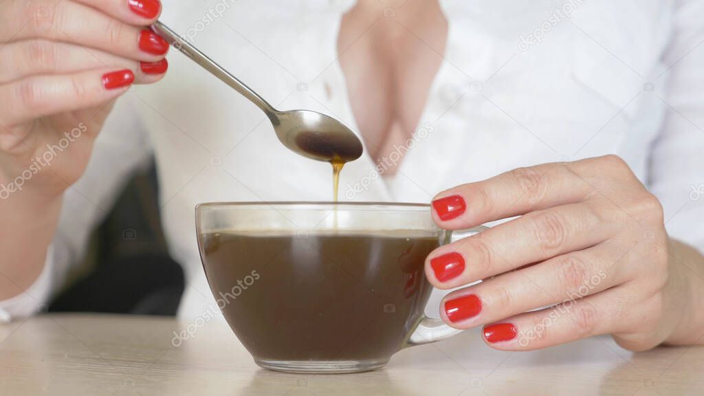 close up of female hands. woman stirring a teaspoon of hot drink in a mug