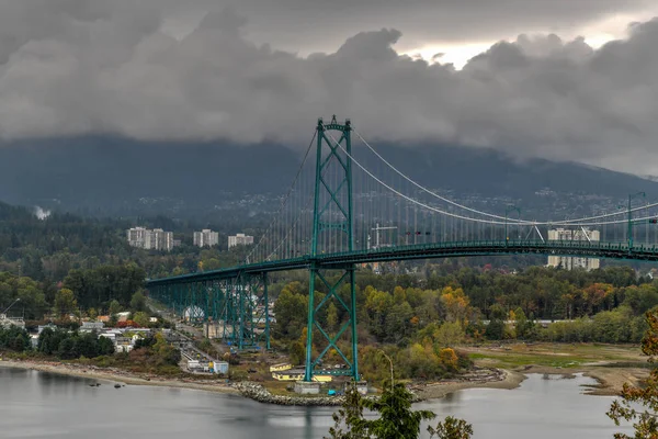 Lions Gate Bridge as seen from Stanley Park in  Vancouver, Canada with autumn leaves. The Lions Gate Bridge, opened in 1938, officially known as the First Narrows Bridge, is a suspension bridge.
