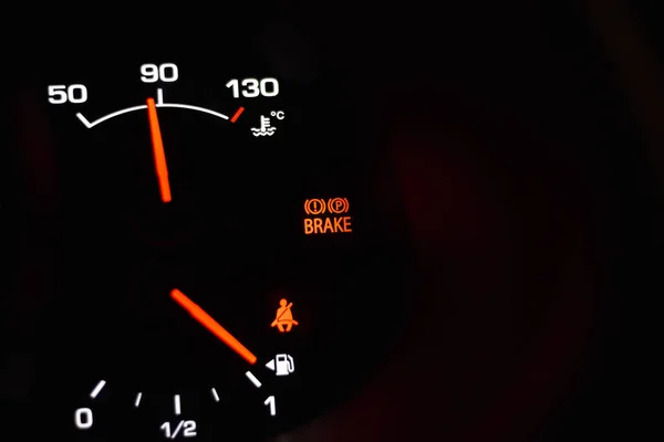 Part of automobile dashboard with parking brake, engine temperature and fuel level indicators
