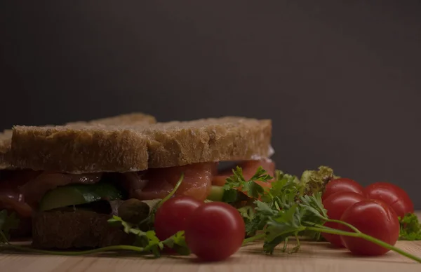 Ciabatta dilimleri kırmızı balık ve siyah arka plan üzerine ahşap plaka üzerinde beyaz krem peynir ile