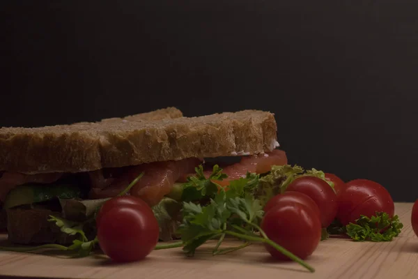 Ciabatta dilimleri kırmızı balık ve siyah arka plan üzerine ahşap plaka üzerinde beyaz krem peynir ile