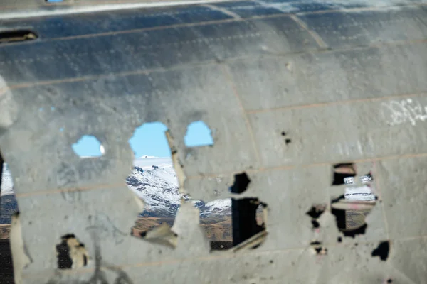Solheimasandur, İzlanda üzerinde terk edilmiş Dc uçak gövde üzerinde deliklerden Mountain view.