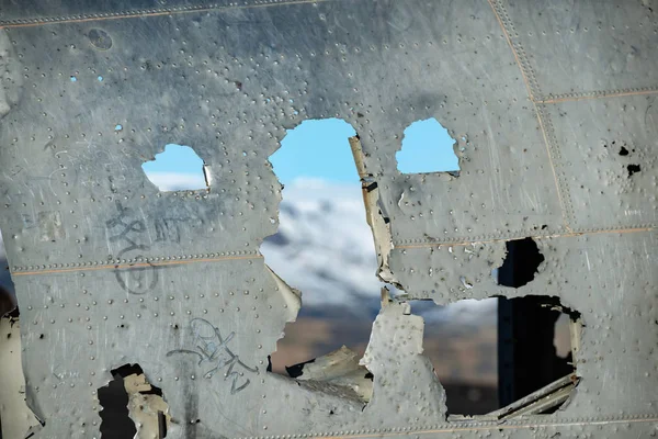 Solheimasandur, İzlanda üzerinde terk edilmiş Dc uçak gövde üzerinde deliklerden odaklanmamış dağ manzaralı.