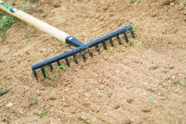 Lavorare in giardino con terra livellamento rastrello. Lavoro in giardino con rastrello. Preparazione del terreno per la semina e la piantagione . — Foto Stock