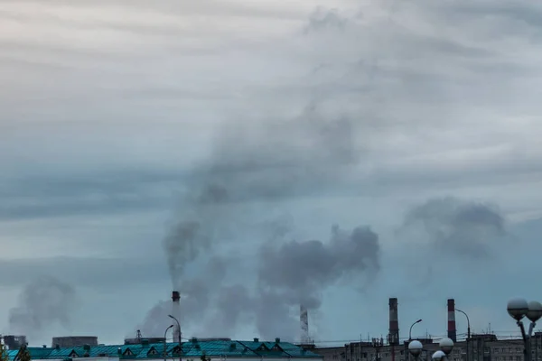 industrial chimneys on cloudy sky background with heavy smoke causing air pollution as environmental problem