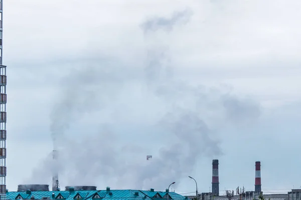 大気汚染を環境問題として引き起こす重い煙を背景に曇った空の背景に産業煙突 — ストック写真