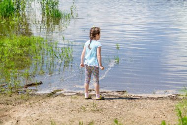 Genç kız nehir kenarında duruyor ve suyu izliyor