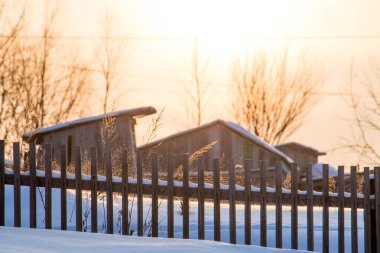 Kırsal kesimde güzel bir kır manzarası arka planda ahşap bir ev ve gün batımında önünde ahşap bir çit. Açık hava eğlencesi konsepti.
