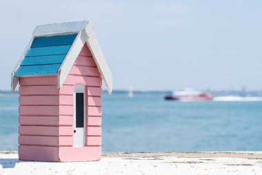 Bir tekne geçtikçe küçük ahşap model plaj kulübe bir duvar overloooking Manş oturdu.