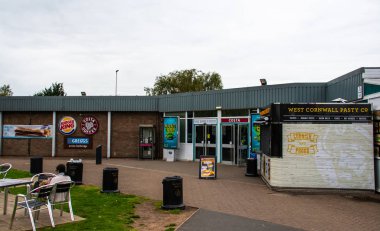 Carlisle, United Kingdom - August 11 2018:   A grey day at Southwaite service station southbound, with signs for Burger King, M&S Simply food, Costa Coffee, Greggs and The West Cornwall Pasty Co clipart