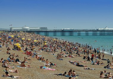 Brighton, Büyük Britanya - 16 Temmuz 2005: Brighton Beaach parlak bir günde iskele önünde güneş zevk güneşlenenbirileri varsa.