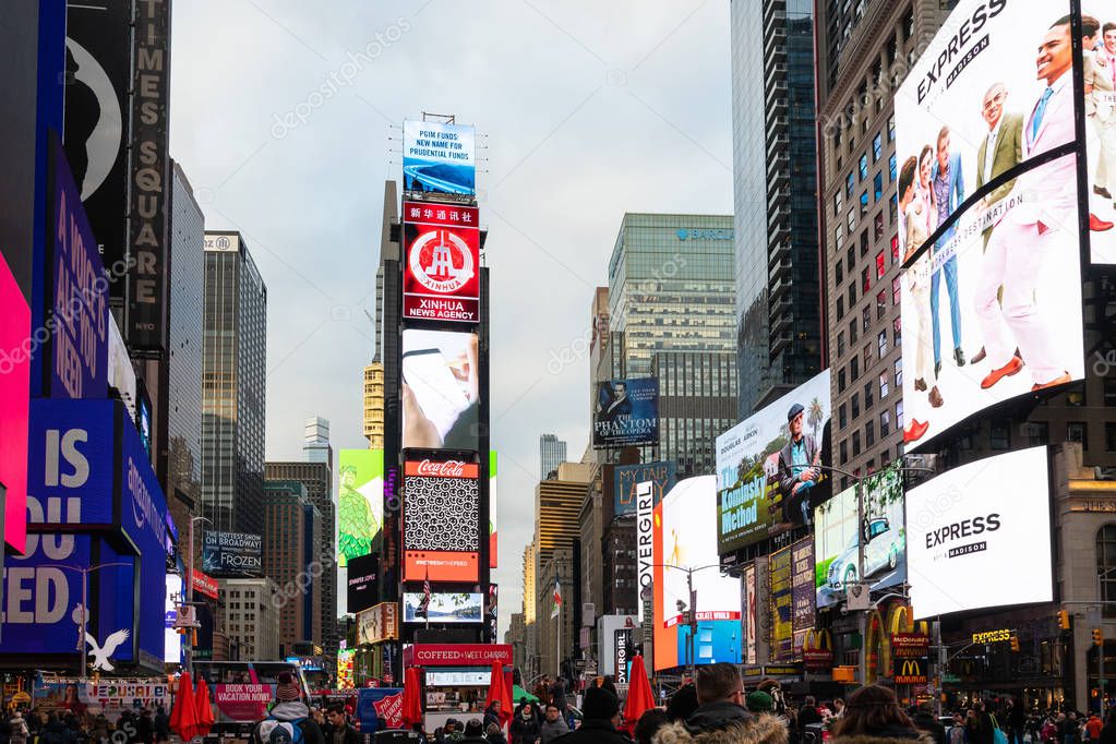 New York City, United States - November 17 2018:   Tourists, shoppers and locals throng amnogst the neon signs and billboards of Times Square