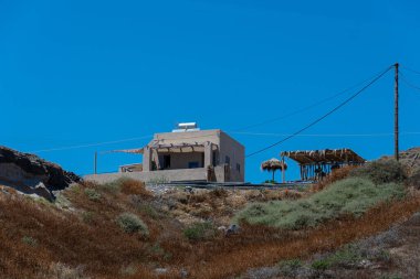 Akrotiri, Yunanistan - 19 Temmuz 2019: Akrotiri Deniz Cephesi kıyısındaki uçurumun tepesinde bir ev