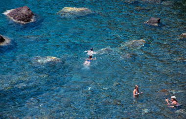 Akrotiri, Yunanistan - 19 Temmuz 2019: Ege Denizi 'nin mavi sularında Akrotiri' nin kızıl plajında yüzen tatilciler