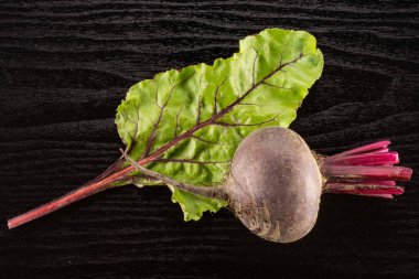 Kırmızı pancar genç ampul ve siyah ahşap zemin üstüne izole bir yaprak yeşil flatlay vie