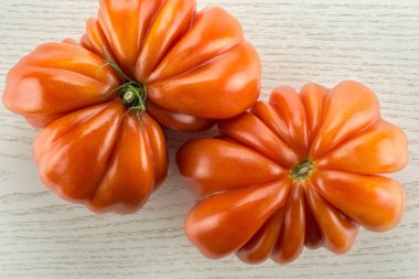 İki biftek domates (kelebek ve çiçek şekilleri) en iyi görünümü gri ahşap arka plan üzerinde bir büyük Olgun kırmızı lastik flatla izole.