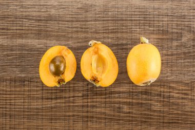 Taze turuncu Japon yenidünya koleksiyon üst iki devrede de bir tohum ve whol ile bir tarih izole kahverengi ahşap arka plan görüntüleme