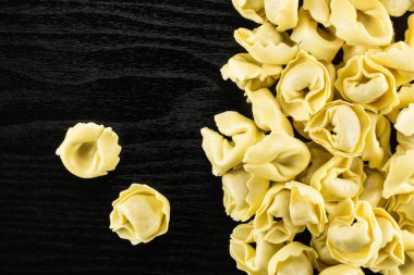 Ham tortellini makarna flatlay siyah ahşap arka plan İtalyan geleneksel dumplin üzerinde