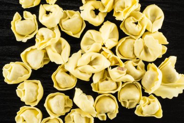 Tortellini pişmemiş makarna flatlay siyah ahşap arka plan İtalyan geleneksel dumplin üzerinde
