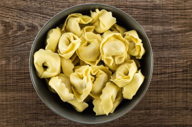 Gri Seramik kase flatlay kahverengi ahşap zemin İtalyan geleneksel dumplin üzerinde ham tortellini makarna