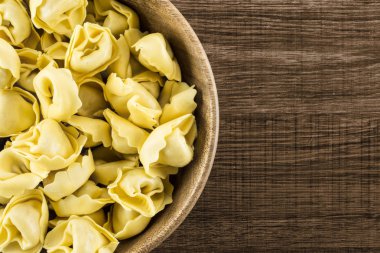 Ahşap kase flatlay kahverengi ahşap zemin İtalyan geleneksel dumplin üzerinde ham tortellini makarna