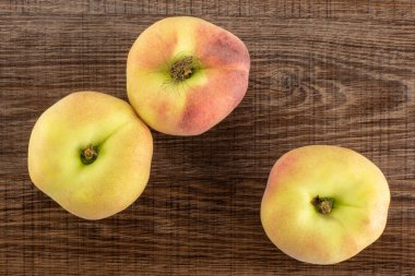 Üç taze olgun Satürn üzerinde kahverengi ahşap adam üstten görünüm şeftali