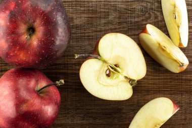 Kırmızı lezzetli elma flatlay kahverengi ahşap zemin iki bütün yarım ve üç dilim üzerinde dilimlenmiş