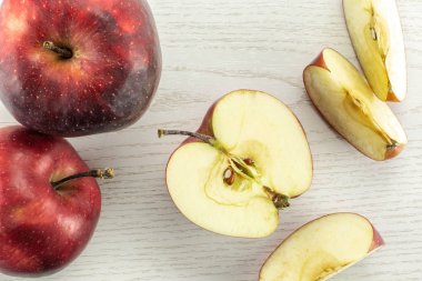 Kırmızı lezzetli elma flatlay gri ahşap arka plan iki bütün yarım ve üç dilim üzerinde dilimlenmiş
