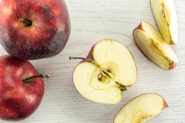 Kırmızı lezzetli elma flatlay gri ahşap arka plan iki bütün yarım ve üç dilim üzerinde dilimlenmiş