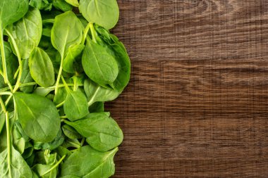 Üzerinde kahverengi ahşap zemin sol corne üstten görünüm taze bebek ıspanak yaprakları