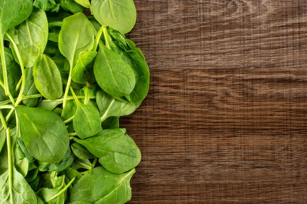 Üzerinde kahverengi ahşap zemin sol corne üstten görünüm taze bebek ıspanak yaprakları