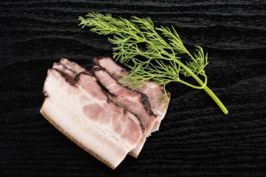 Üç dilim İngilizce pastırma siyah ahşap üzerine dereotu flatlay yaylı grubu