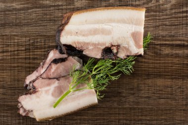 Üç grup İngilizce pastırma tek parça dereotu flatlay sapı ile kahverengi ahşap üzerine dilimler.