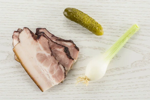 Üç dilim İngilizce pastırma bir tuzlu salatalık ve taze soğan flatlay gri Wood ile Grup