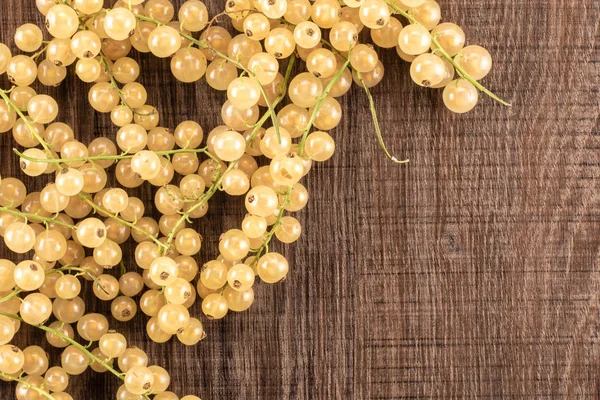 Lot of whole fresh white currant berry blanka variety left upper corner flatlay on brown wood
