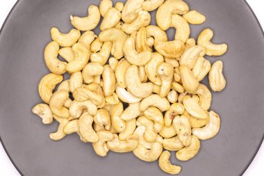 Tüm çiğ kaşu fındık üzerinde beyaz arka plan üzerinde izole gri seramik tabak flatlay sürü