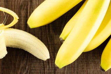 Bütün taze sarı muz ve kahverengi ahşap üzerine bir açılan flatlay çok