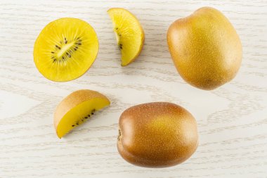 İki yarım bütün grup iki dilim taze altın kahverengi Kivi Meyve sungold çeşitli flatlay gri Wood