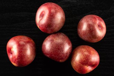 Beş bütün taze pluot interspecific Erik çeşitli flatlay siyah ahşap üzerine Grup