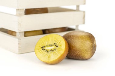 Bütün yarısı çok taze altın kahverengi Kivi Meyve sungold çeşitli ile ışık ahşap sandık üzerinde beyaz izole kivi dolu
