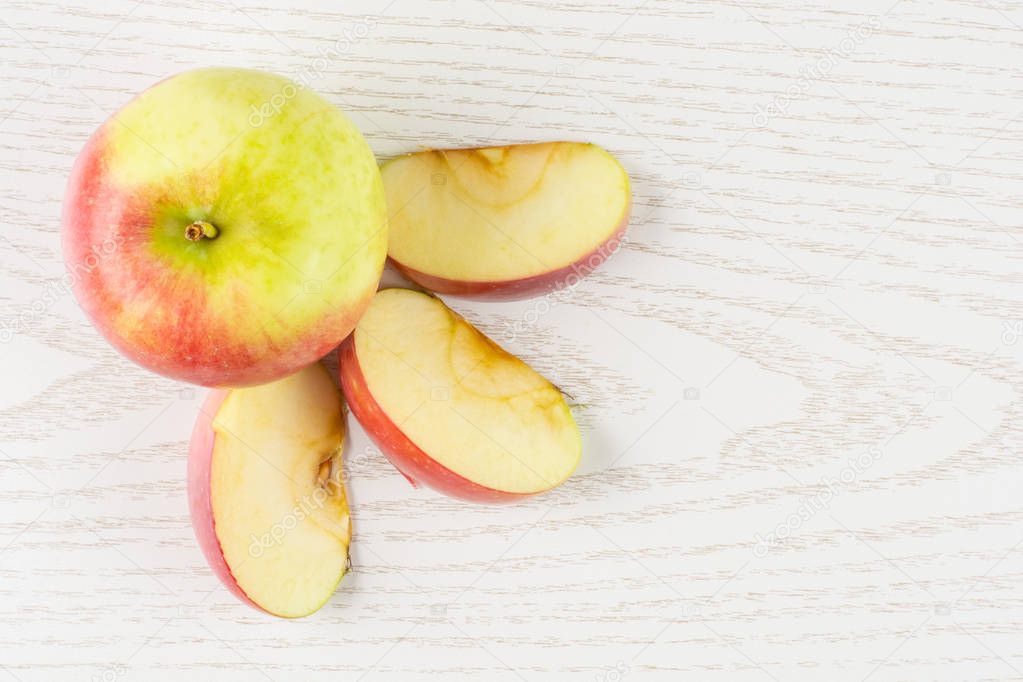 Group of one whole three slices of fresh red apple james grieve variety flatlay on grey wood