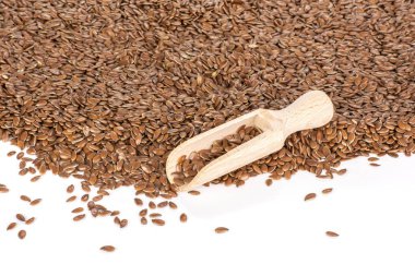 Bütün taze kahverengi flaxseeds beyaz arka plan üzerinde izole ahşap kepçe ile sürü