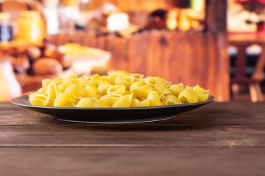 Tüm çiğ sarı makarna conchiglie çeşitli arka plan içinde rustik ahşap mutfak gri Seramik plaka üzerinde çok